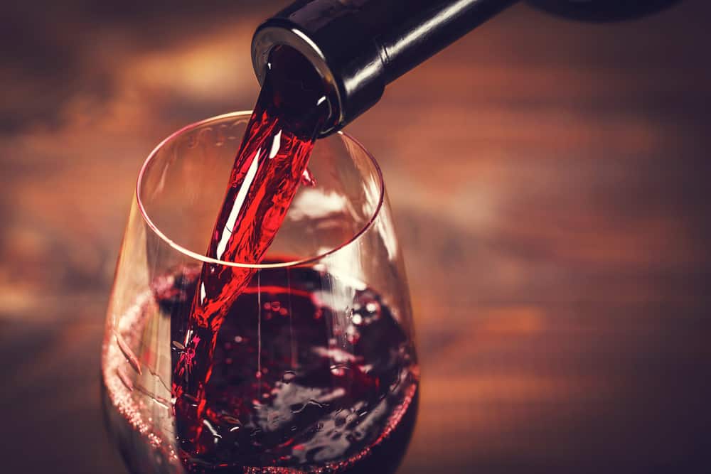Rødvin der skænkes fra flaske til glas.