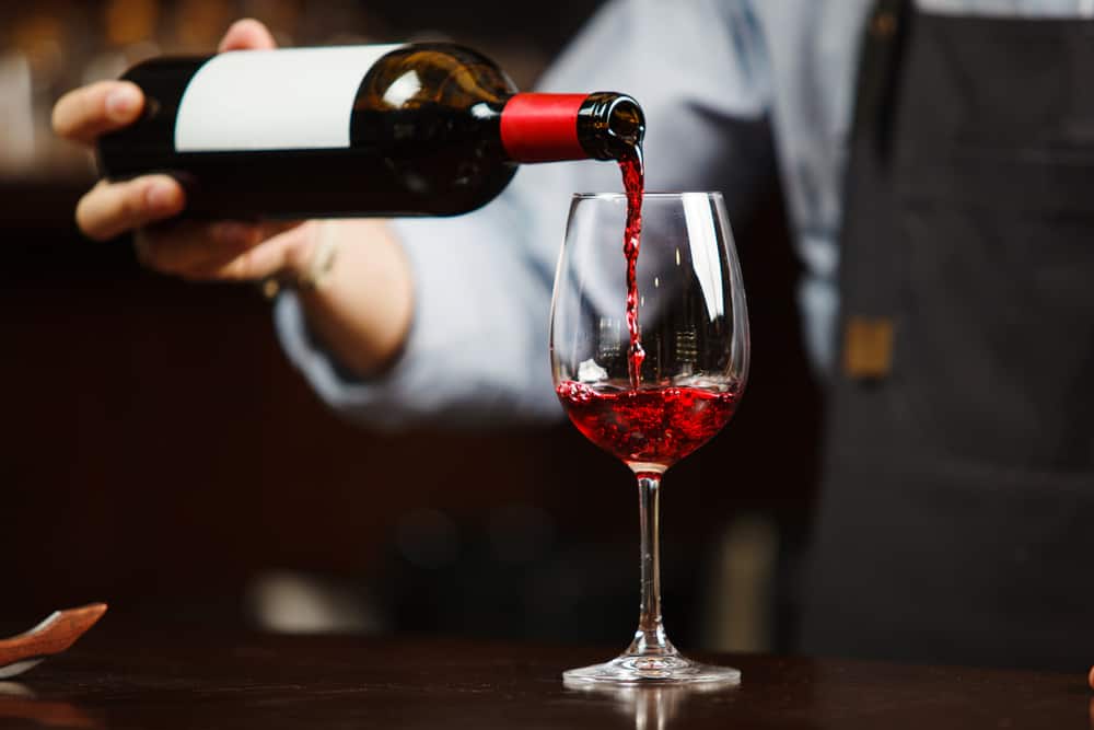 Tjener der skænker vin op i et vinglas.