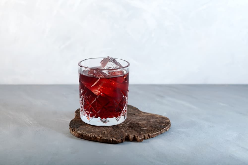Vermouth drink i et glas placeret på en træplade på et bord.